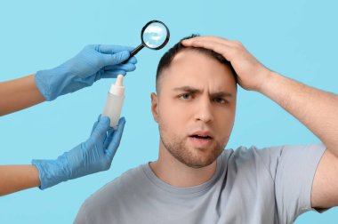 Genç adam ve doktor ellerinde büyüteçle mavi arka planda saç büyütme serumu tutuyorlar.