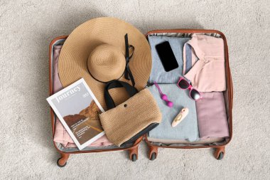 İçinde giysiler, plaj aksesuarları, seks oyuncakları ve cep telefonu olan açık bir bavul.