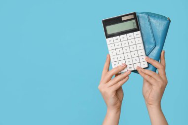Hesap makinesi ve cüzdanı renk arkaplanında olan kadın elleri, yakın plan