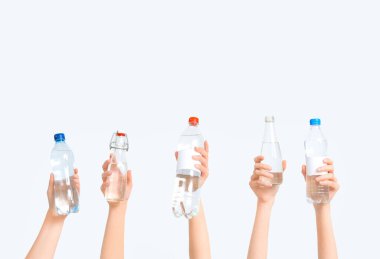 Beyaz arka planda farklı su şişeleri olan kadın eller.