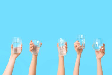 Renkli arka planda farklı su bardakları olan kadın eller, yakın plan