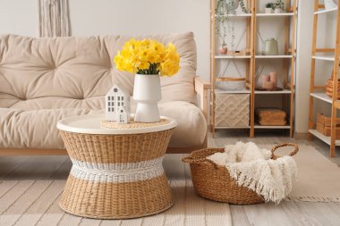 Güzel oturma odasında bir buket narsist çiçekli rahat bir kanepe ve kahve masası.