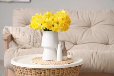 Oturma odasında vazo dolusu narsisli kahve masası.