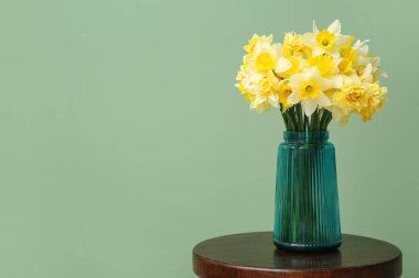 Yeşil arka planda Narcissus çiçekli vazo