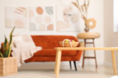 Işıl ışıl oturma odasının içinde rahat bir kanepe, çiçek ve kahve masası, bulanık bir görüntü.