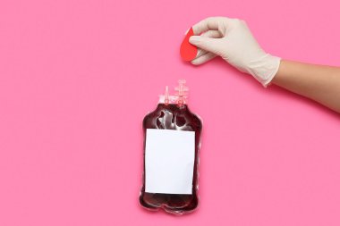 Pembe arka planda kan nakli için elinde kan torbası olan bir kadın. Dünya kan bağışı günü.