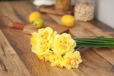 Mutfaktaki ahşap masanın üzerinde güzel bir buket nergis çiçeği, yakın plan.