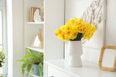 Oturma odasında nergisli vazo var.