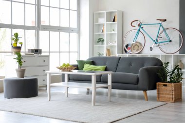 Siyah kanepesi, sehpası, bisikleti ve raf ünitesi olan şık bir oturma odası.