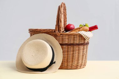 Beyaz arka planda piknik için lezzetli yemek, şarap ve şapka sepeti.