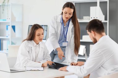 Genç doktorlar klinikteki masada röntgen görüntülerini inceliyor.