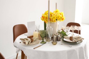 Beautiful table setting with daffodils and candles for wedding celebration in room