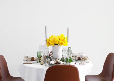 Beautiful table setting with daffodils and candles for wedding celebration in room