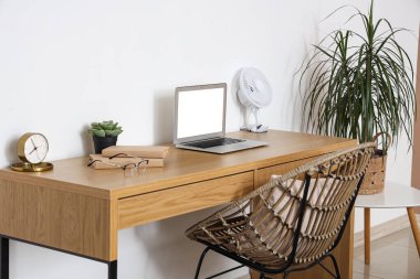 Modern elektrikli vantilatör ve laptop ofis masasında.
