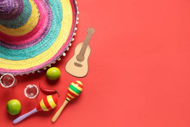 Meksika marakaları, sombrero, tekila ve kırmızı arka planda kağıt ukulele. Cinco de Mayo