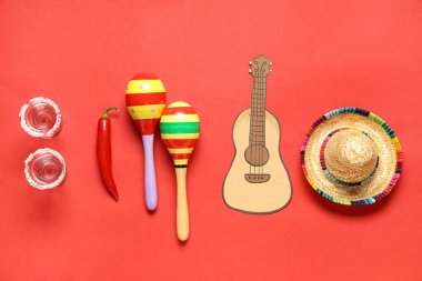 Meksika marakaları, sombrero, tekila ve kırmızı arka planda kağıt ukulele. Cinco de Mayo