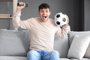 Genç adam TV 'de futbol maçı izliyor.