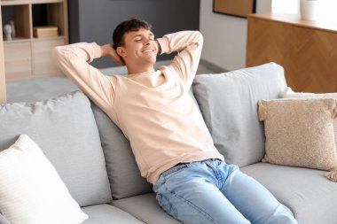 Evde koltukta oturan genç adam