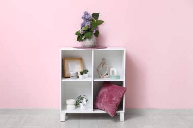 Odadaki pembe duvarın yanındaki raflarda leylak dalları olan vazo.