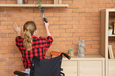 Tekerlekli sandalyedeki genç bir kadın evdeki sondaj rafını deliyor.