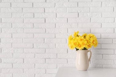 Oturma odasındaki masada sürahide nergis çiçekleri