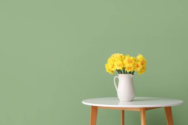 Nergis çiçekleri sehpanın üzerinde yeşil arka planda.