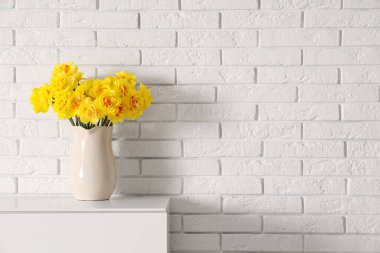 Oturma odasındaki çekmecenin üstündeki sürahide nergis çiçekleri