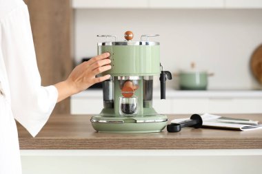 Güzel genç bir kadın, modern kahve makinesiyle espresso yapıyor, yakın plan.