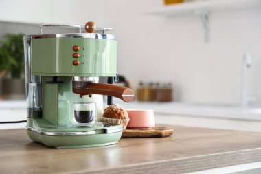 Modern kahve makinesi. Mutfaktaki masada bir fincan sıcak espresso ve kek.