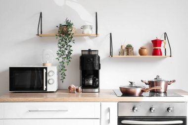 Mutfaktaki masada kapuçino ve kek ile modern kahve makinesi.