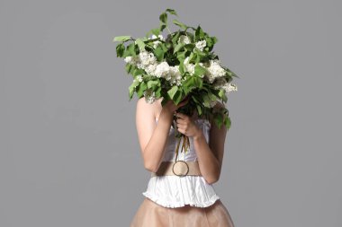 Young woman with bouquet of blooming white lilac flowers on grey background