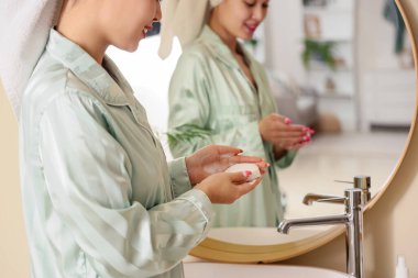 Lavabonun yanında sabunu olan genç bir kadın, yakın plan.