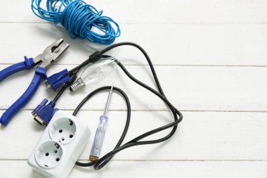 Elektrikçi aletleri, uzatma kablosu ve beyaz ahşap arka plandaki kablolar