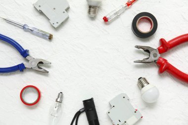 Beyaz grunge arka planda elektrikçi aletleri ve ampullerden yapılmış çerçeve
