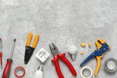 Gri grunge arka planda elektrikçi aletleri, ampuller ve elektrik soketi