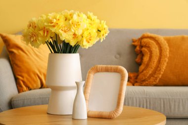 Oturma odasındaki sehpanın üzerinde nergis çiçekleri olan vazo.