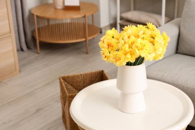 Oturma odasında nergis çiçeği olan bir vazo.