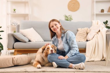 Şirin bir Avustralya çoban köpeği olan genç bir kadın evde yerde oturuyor.