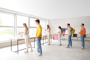 Oy kullanma merkezindeki ABD bayraklarıyla oy sandıklarının yakınındaki gençlere oy vermek