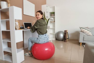 Genç Asyalı kadın evde dizüstü bilgisayar kullanıyor.