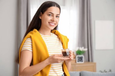 Evinde bir fincan sıcak kahveyle güzel genç bir bayan.