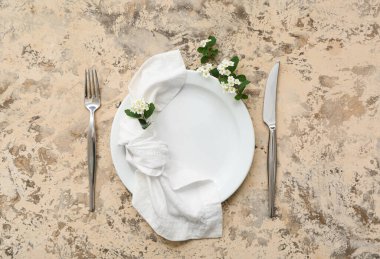 Tabak, çatal bıçak, peçete ve arkaplanda çiçek açan dallarla güzel bir masa.