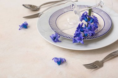 Tabaklar, çatal bıçak takımları, şarap kadehleri ve çiçeklerle aydınlık arka plan, yakın plan.