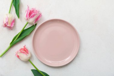 Pembe tabağı ve açık arkaplanda çiçekleri olan güzel bir masa.