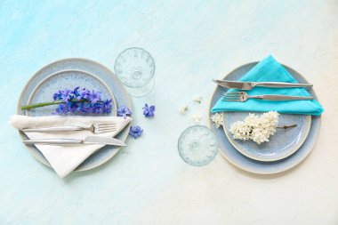 Tabaklar, çatal bıçaklar, peçeteler, bardaklar ve çiçeklerle dolu güzel bir masa.