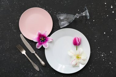 Tabaklar, çatal bıçak takımı, cam ve çiçeklerle dolu güzel bir masa.