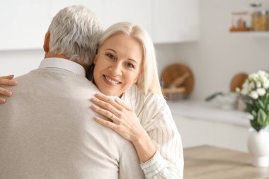 Olgun bir kadın, evlilik yıldönümlerinde kocasına sarılıyor.