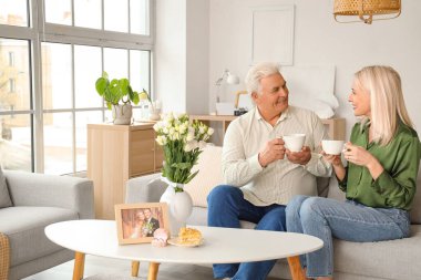 Evde çay içip evlilik yıldönümlerini kutlayan olgun bir çift.