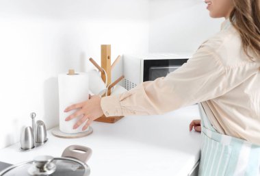 Ev hanımı mutfakta kağıt havlu alıyor, yakın plan.