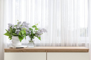 Pencerenin yanındaki çekmecelerde çiçek buketleri olan vazolar.